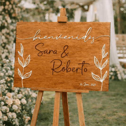 Cartel boda madera con palabra bienvenidos en relieve acrílico blanco y hojas botánicas grabadas