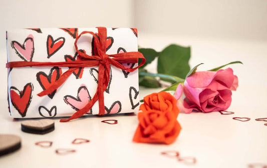 Regalo personalizado para pareja envuelto con patrón de corazones y rosa, ideal para San Valentín o aniversario