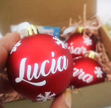 Adorno navideño de bola dorada con nombre grabado, detalle elegante para árbol de Navidad tradicional.