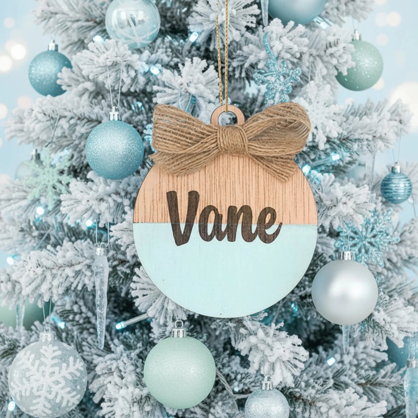 Detalle de nombre grabado a láser sobre bola de Navidad de madera pintada a mano