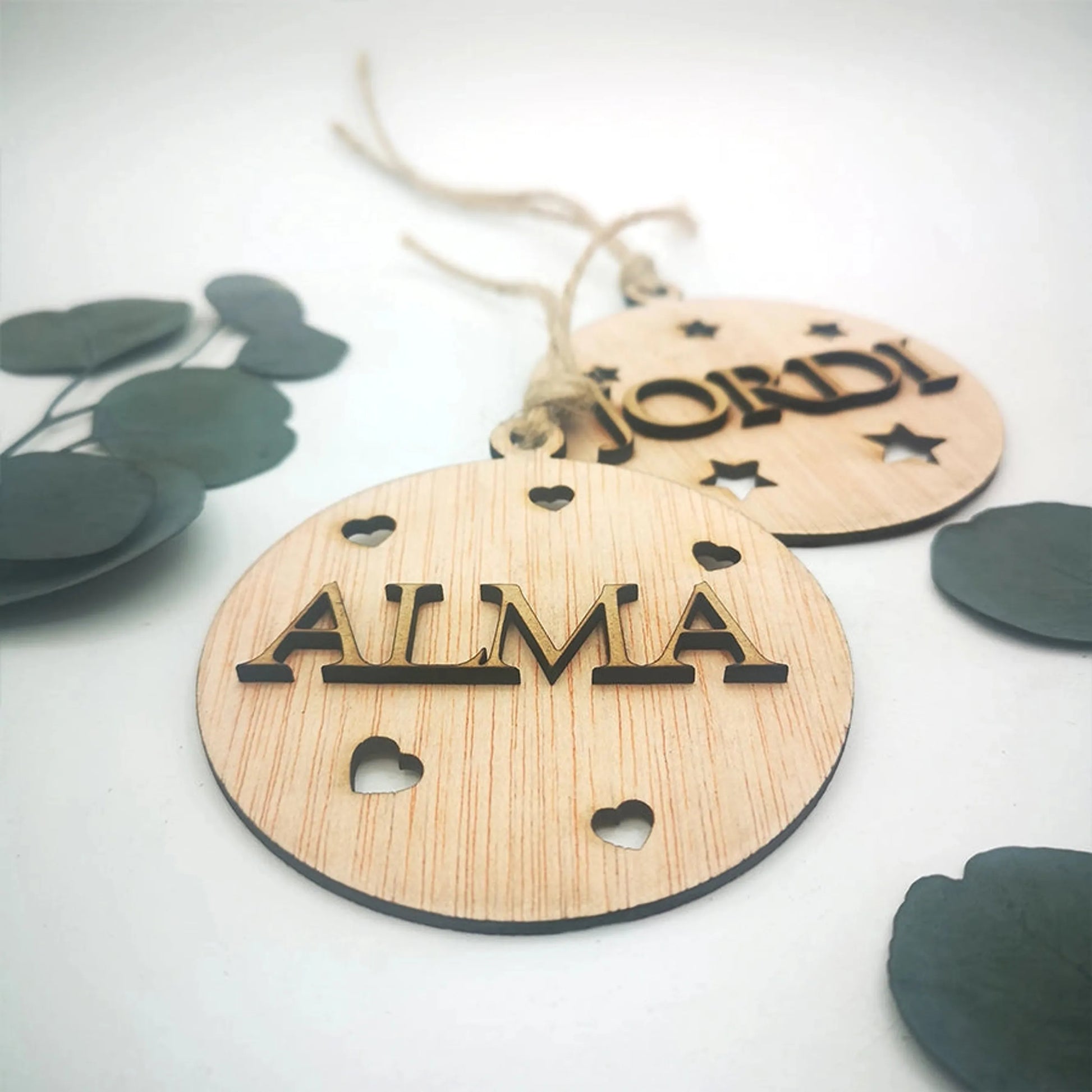 Detalle de nombre tallado a láser en madera DM sobre bola de Navidad artesanal de calabó