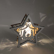 Iluminación artesanal navideña en madera con estrella y escena del pesebre.
